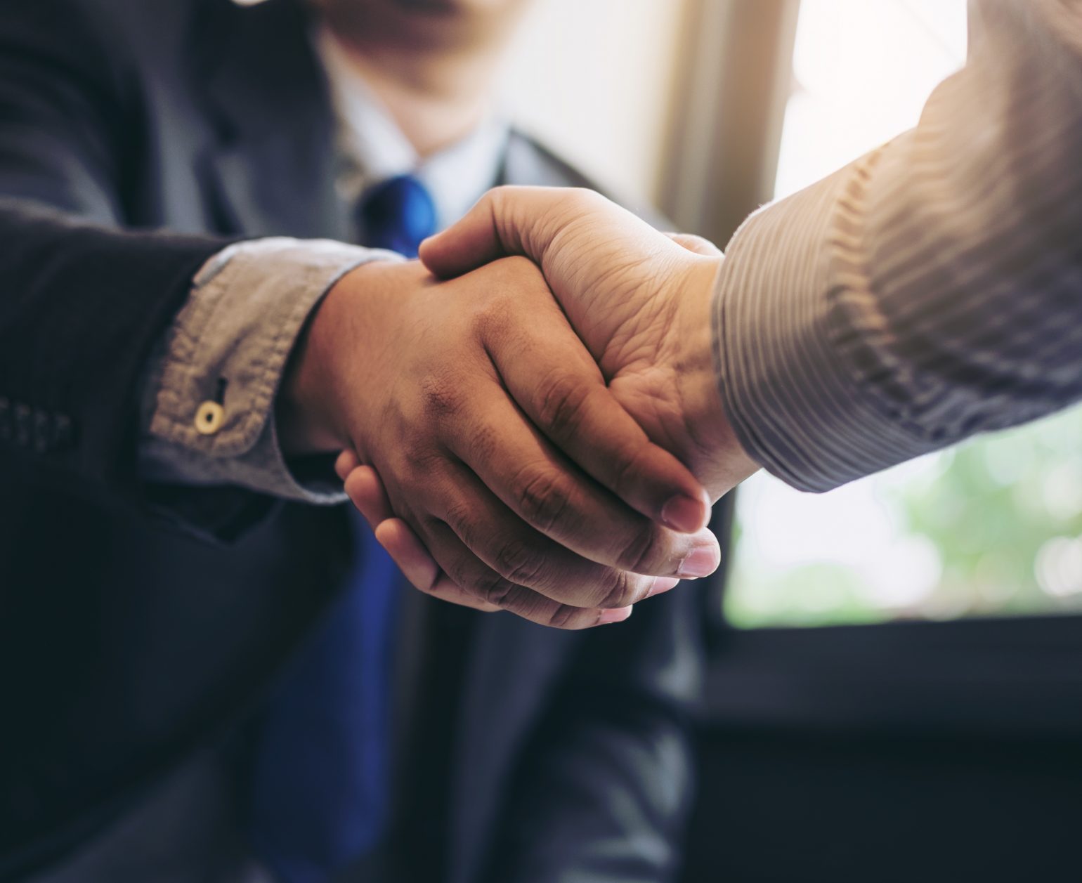 Two business men shaking hands during a meeting to sign agreement and become a business partner, enterprises, companies, confident, success dealing, contract between their firms.