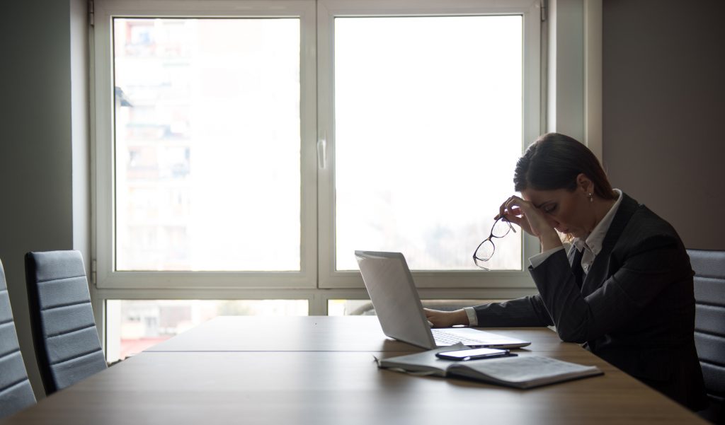 Business person in a posture of despair sitting in an empty conference room