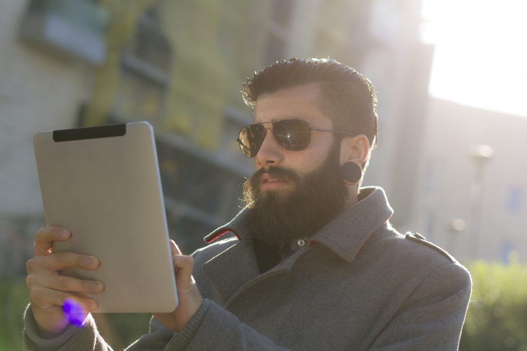 Bearded man in sunglasses using tablet